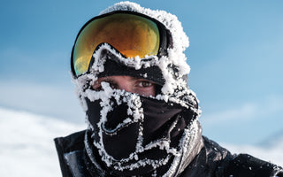 Snow covered racer with ski goggles on their head. Only their eyes are visible. 