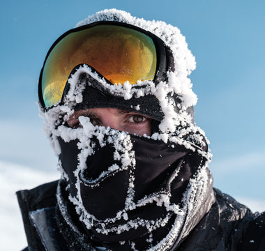 Snow covered racer with ski goggles on their head. Only their eyes are visible. 